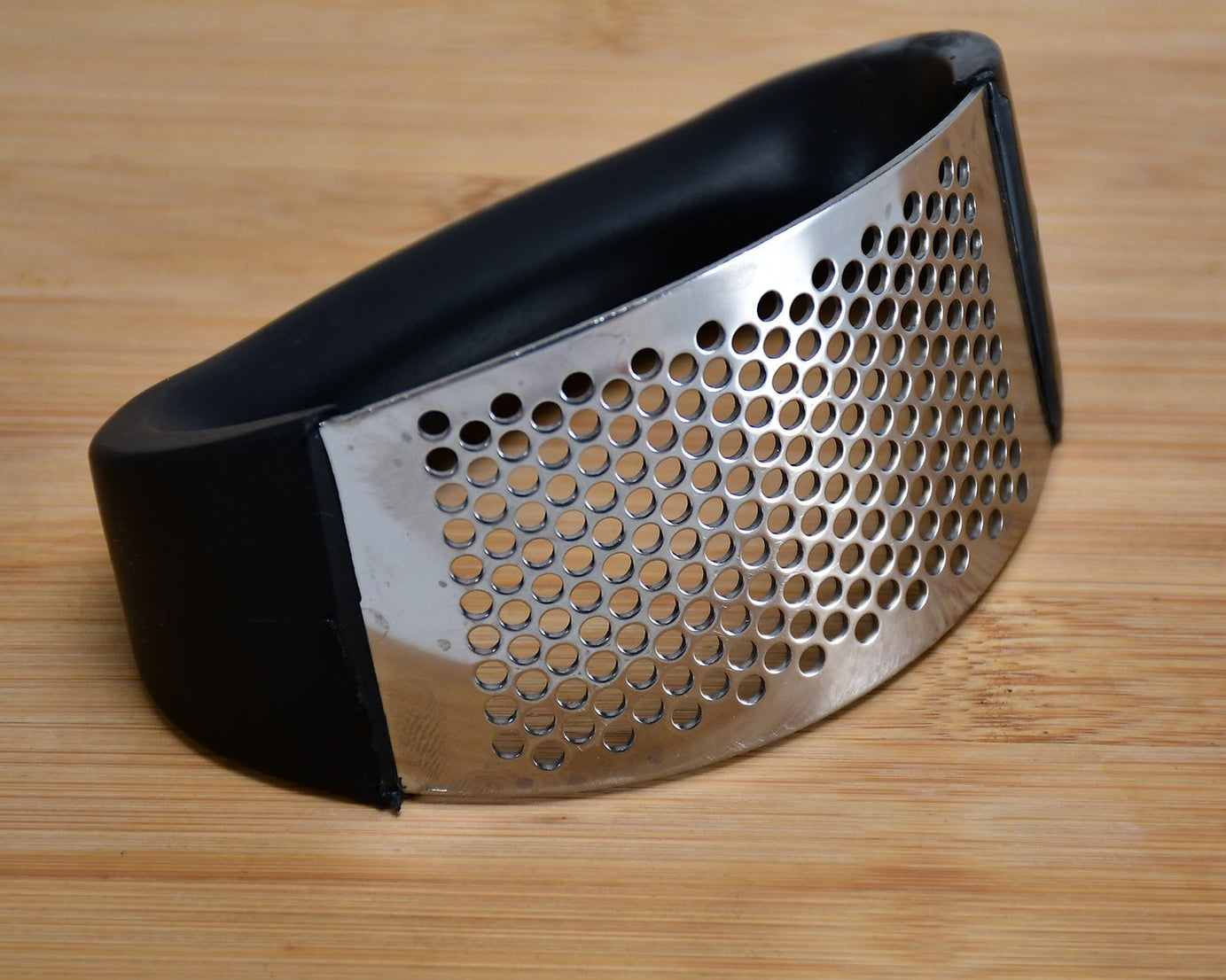 Stainless steel garlic crusher with ergonomic handle in multicolor.