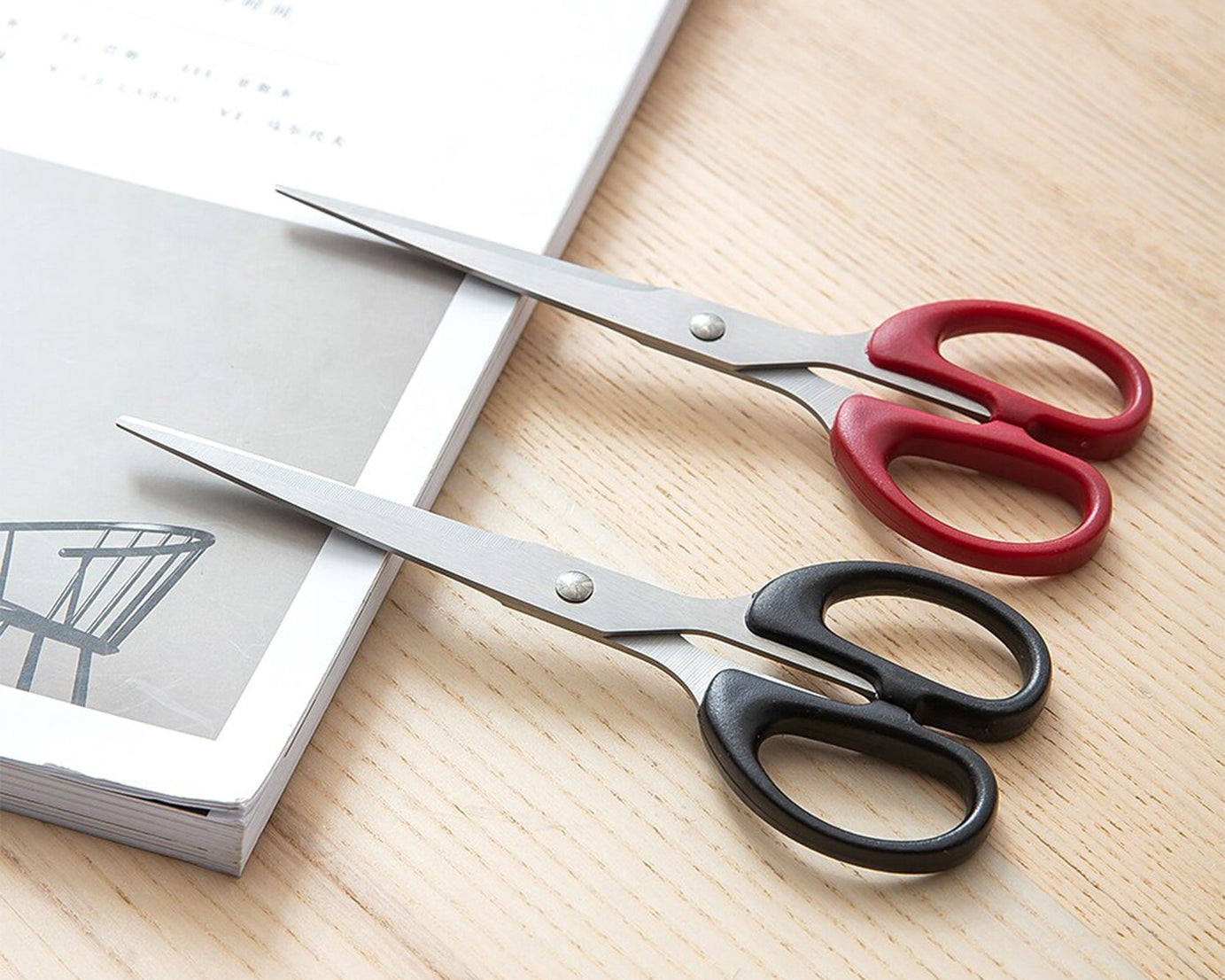 Top-down view of the scissors, emphasizing their stainless steel blades and plastic handle grip